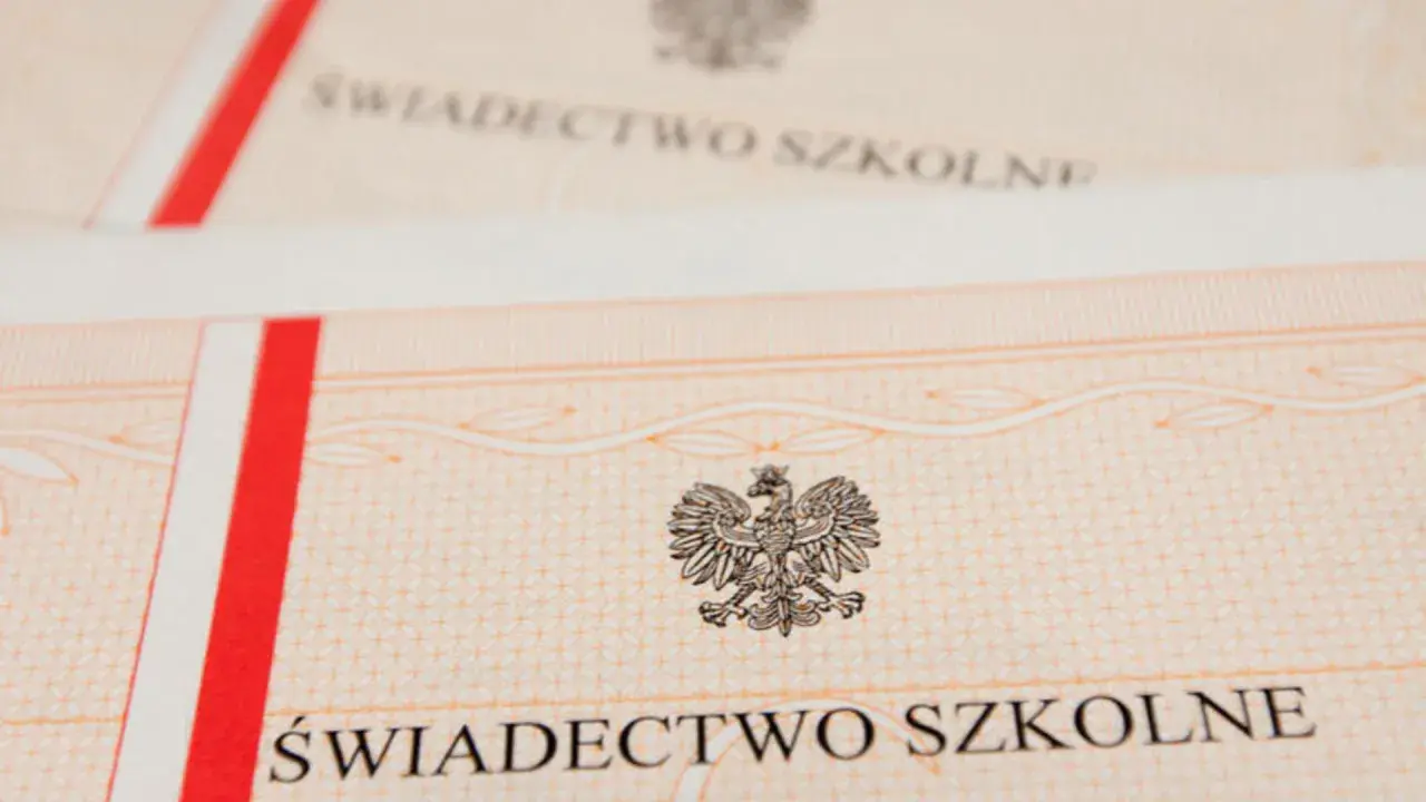 Zbliżenie na świadectwo szkolne z godłem Polski. Czerwono-biały pasek po lewej stronie.