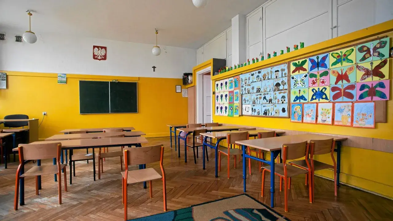Pusta klasa z kolorowymi pracami dzieci na ścianie. Idealne miejsce, kiedy wolne od szkoły, by poczuć się jak uczeń.