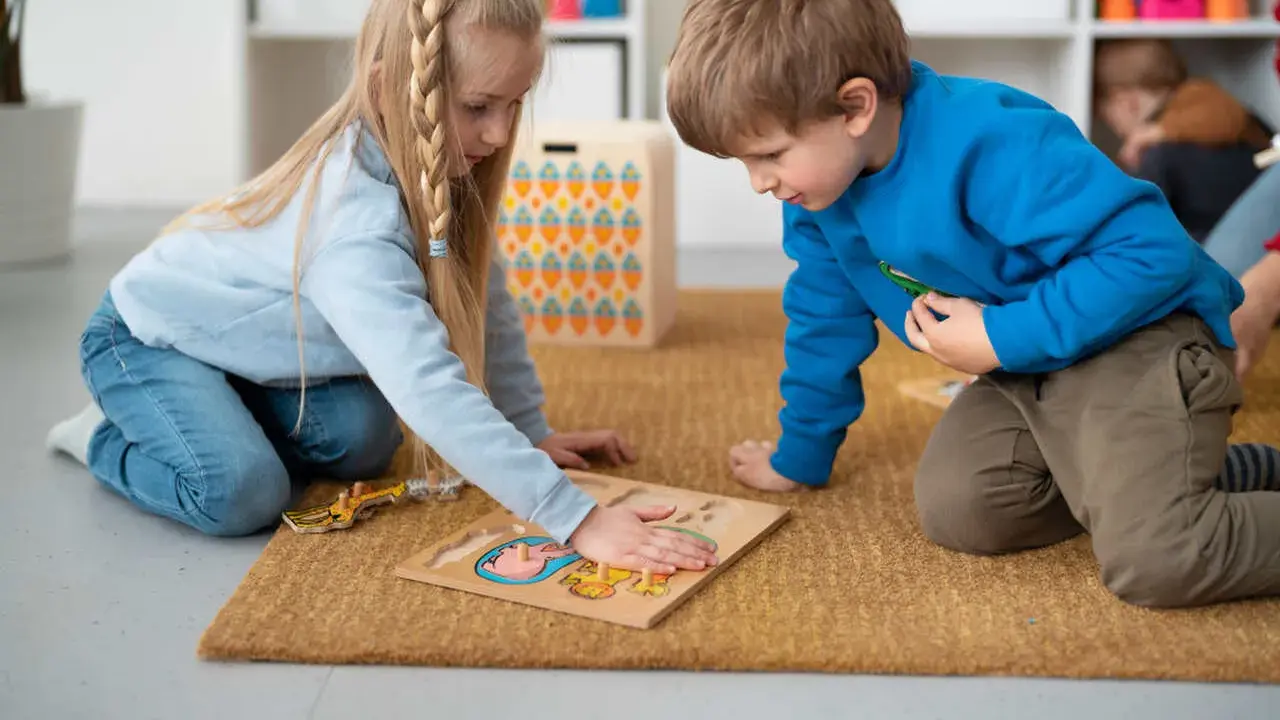 Dzieci na dywanie układają puzzle, ćwicząc spostrzegawczość. To nauka przez zabawę, zgodna z metodą Montessori.