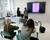 Lekcja religii w szkole. Czy religia wlicza się do średniej? Nauczycielka w habicie i uczniowie patrzą na ekran z informacją o Drodze Krzyżowej.