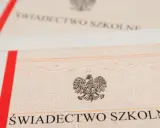 Zbliżenie na świadectwo szkolne z godłem Polski. Czerwono-biały pasek po lewej stronie.