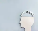 Biały profil głowy z literami tworzącymi łuk nad nią. Litery układają się w słowo "APHASIA", symbolizując afazję motoryczną.