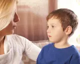Kobieta rozmawia z chłopcem, który ma afazję mowy. Skupienie na twarzach i próbie komunikacji.
