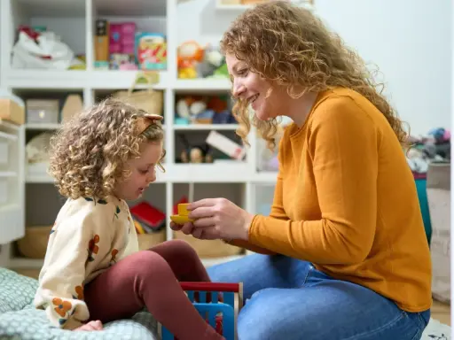 Mama z córką bawią się w pokoju pełnym zabawek. Czy urlop wychowawczy wlicza się do stażu pracy? To pytanie nurtuje wiele mam.