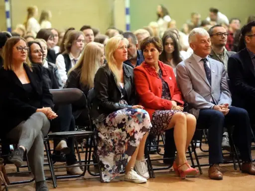 Uczestnicy siedzą na krzesłach, wśród nich widać osoby, które mogą być na radzie pedagogicznej.
