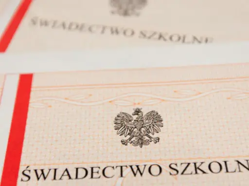 Zbliżenie na świadectwo szkolne z godłem Polski. Czerwono-biały pasek po lewej stronie.