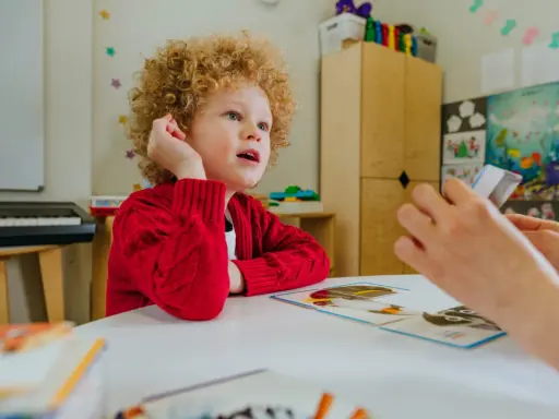 Chłopiec z kręconymi włosami, u którego podejrzewa się zespół Aspergera, uczy się z kart obrazkowych.
