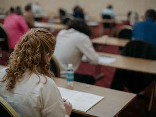 Uczestnicy piszą egzamin z angielskiego. Zastanawiają się, ile trwa egzamin z angielskiego, skupieni na zadaniach.