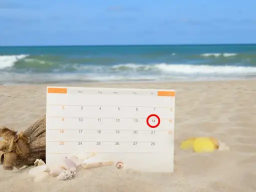 Kalendarz na plaży z zaznaczonym 14. dniem. Czas na urlop bezpłatny i relaks nad morzem.