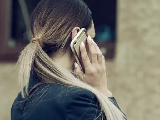 Kobieta rozmawia przez telefon, być może dowiadując się o **siłę wyższą kodeks pracy**.
