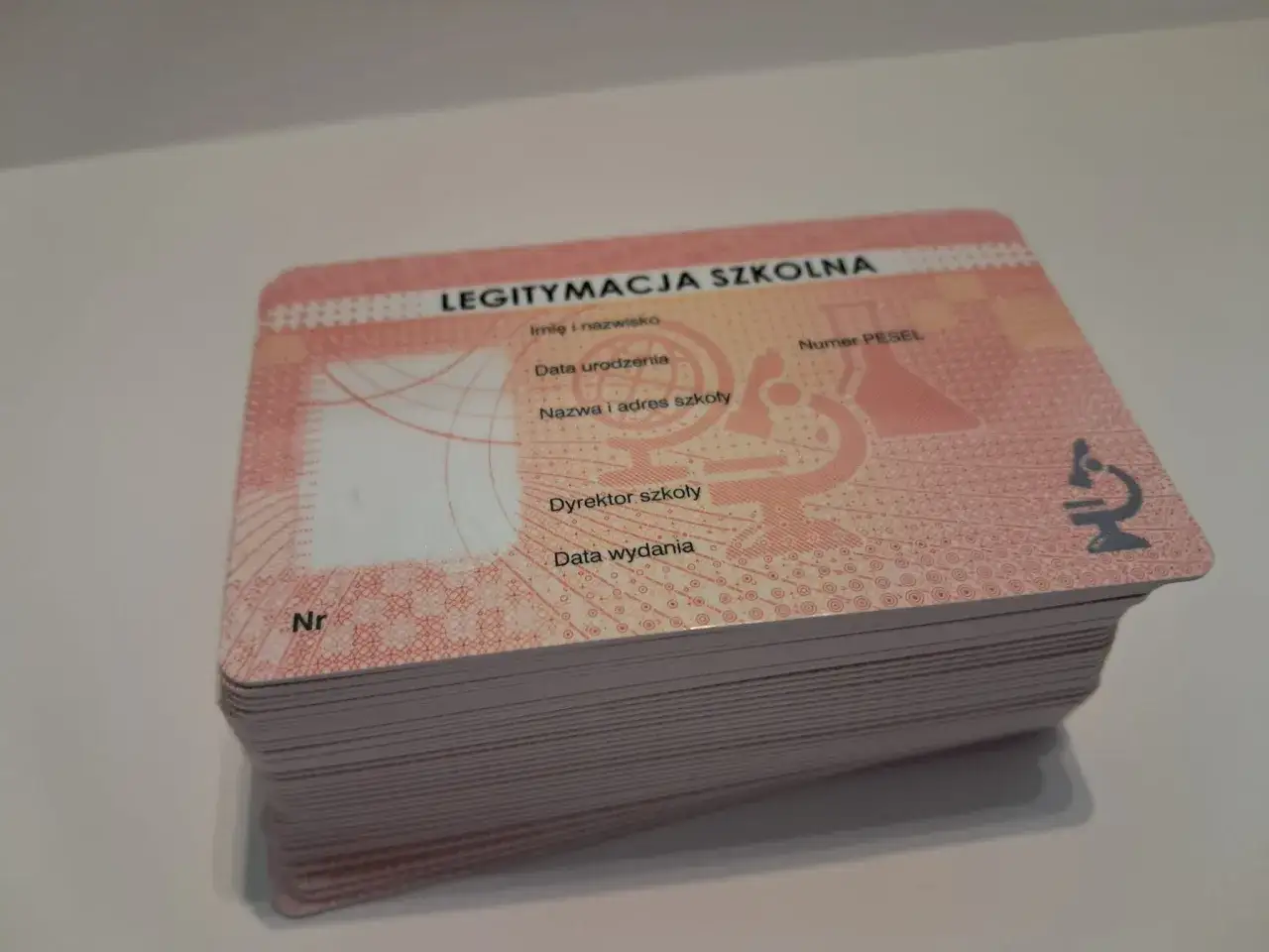 Stos nowych legitymacji szkolnych z miejscem na zdjęcie, imię, nazwisko, datę urodzenia i PESEL.